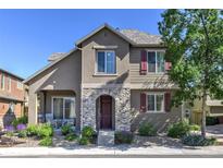 Charming two-story home featuring a stone-accented entrance and covered patio, surrounded by lush landscaping at 10550 Ashfield St, Highlands Ranch, CO 80126