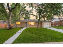 Charming brick home with mature trees, lush green lawn, and welcoming walkway leading to the front door at 2391 S Quitman St, Denver, CO 80219