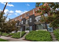 Modern townhome with balconies, contrasting wood and dark siding, and landscaped front entrances under a blue sky at 1534 Irving St, Denver, CO 80204