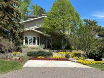 Charming two-story home with landscaped yard and colorful flowerbeds leading to the front entrance at 6843 Fairview Dr, Boulder, CO 80303