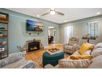 Inviting living room with a cozy fireplace, modern ceiling fan, and comfortable seating arrangement at 2300 Jasmine St, Denver, CO 80207