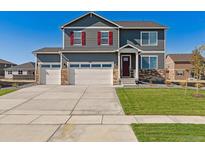 Charming two-story home with a three car garage, green lawn, and red shutters at 4211 Sandstone Dr, Mead, CO 80504
