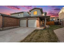 Two-story home featuring an attached two-car garage, brick facade, and manicured lawn during a scenic sunset at 12603 Eudora St, Thornton, CO 80241