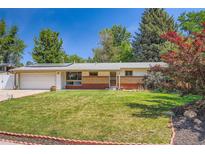 Charming ranch style home featuring a brick facade, solar panels, and a well-manicured front lawn at 8075 Sunset Dr, Lakewood, CO 80214