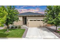 Charming single-story home with a stone facade, well-manicured lawn, and attached two-car garage at 722 Eva Peak Dr, Erie, CO 80516