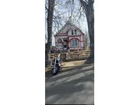 Charming two-story home with red and white accents, complemented by a small front yard and a motorcycle parked in front at 3854 N Cook St, Denver, CO 80205