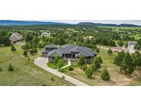 Stunning aerial view of a luxury home surrounded by lush greenery and a long driveway at 843 Long Timber Ln, Monument, CO 80132
