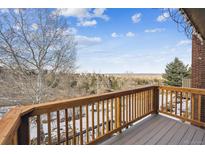 View of a deck with wooden railings and a nice view of nature and bare trees on a partially cloudy day at 148 S Holman Way, Golden, CO 80401