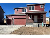 Two-story home featuring a two-car garage, covered porch with brick accents, and a traditional front door at 747 Sunflower Dr, Brighton, CO 80601