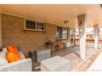 Relaxing covered patio with wicker furniture and brick accents, perfect for outdoor living at 2465 Yates N St, Denver, CO 80212