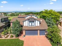 Charming two-story home with a three-car garage, lush landscaping, and mountain views in the background at 1175 Oakhurst Dr, Broomfield, CO 80020