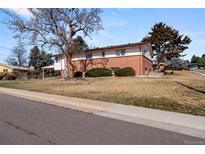 Charming home featuring a well-manicured lawn, red brick facade, and mature trees at 2799 S Ingalls Way, Denver, CO 80227