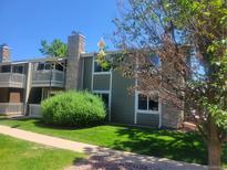 Attractive condo exterior with a stone chimney, tidy green lawn, and mature trees at 4400 S Quebec St # 108L, Denver, CO 80237