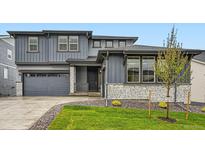 Charming two-story home with gray siding, stone accents, manicured lawn, and attached two car garage at 630 Sunrise St, Erie, CO 80516