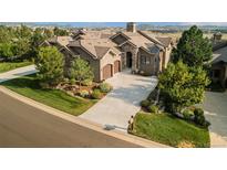 Stunning home featuring a stone facade, lush landscaping, and a long driveway leading to a two-car garage at 5149 Le Duc Ln, Castle Rock, CO 80108