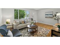 Bright living room with hardwood floors, neutral-toned sofa, stylish rug, and a large window showcasing the outdoor view at 1376 Ivanhoe St, Denver, CO 80220