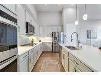 This kitchen features white cabinetry, stainless steel appliances, and a large island with a sink at 1588 Blackwood Ct, Erie, CO 80516