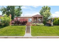 Charming brick home with a covered front porch and beautiful landscaping at 5044 W Moncrieff Pl, Denver, CO 80212
