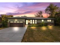 Charming single-story home with brick accents, a spacious driveway, and lush landscaping under a lovely sunset sky at 5054 W 61St Dr, Arvada, CO 80003