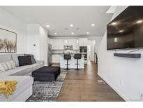 Open-concept living room with modern decor, hardwood floors, and seamless flow into the kitchen at 8331 Farmers Way, Highlands Ranch, CO 80129