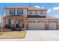 Two-story home boasts a three car garage, brick accents, neutral color, and well-manicured lawn at 1301 Sidewinder Cir, Castle Rock, CO 80108