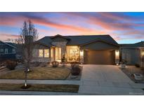 Charming home with stone accents, well-manicured lawn, and two car garage during a beautiful sunset at 12371 Red Fox Way, Broomfield, CO 80021