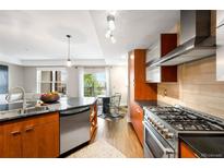 Modern kitchen featuring stainless steel appliances, dark countertops, and light wood cabinets with an adjacent breakfast nook at 2240 N Clay St # 309, Denver, CO 80211