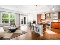 Open-concept living room with hardwood floors, a modern kitchen and a sliding glass door to a balcony at 2240 N Clay St # 309, Denver, CO 80211