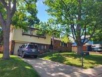 Charming two-story home with a well-manicured lawn and mature trees lining the property at 6649 Van Gordon Ct, Arvada, CO 80004