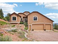 Stunning stucco home featuring a three-car garage and beautiful rock landscaping at 13084 Deer Ridge Way, Larkspur, CO 80118