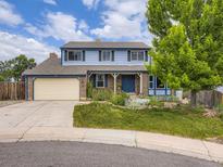 Charming two-story home featuring a well-manicured lawn, brick accents, and a two-car garage at 7296 S Flower St, Littleton, CO 80128