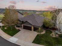 Stunning aerial view of a home with a sprawling lawn, three-car garage, and beautiful mountain views at 828 Rabbit Run Dr, Golden, CO 80401