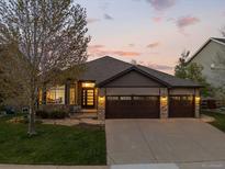 Charming ranch-style home showcasing stone accents, a spacious driveway, and a well-manicured lawn at sunset at 828 Rabbit Run Dr, Golden, CO 80401