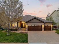 Charming home featuring a three-car garage, stone accents, and professionally landscaped yard at 828 Rabbit Run Dr, Golden, CO 80401