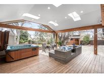 Cozy back porch with a hot tub, wood beams, skylights and stylish patio furniture for outdoor relaxation at 13969 W 23Rd Ave, Golden, CO 80401
