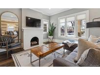 Cozy living room featuring a brick fireplace, large windows, and modern decor at 1626 Albion St, Denver, CO 80220