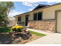 Charming single-story home featuring a stone accent wall, well-manicured lawn, and inviting outdoor seating at 6147 Dunraven, Golden, CO 80403