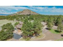 Stunning aerial view of the property with beautiful mountain views and lush landscaping at 3842 Estates Cir, Larkspur, CO 80118
