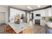Bright kitchen featuring white cabinetry, granite countertops, and a large center island at 4950 Mt Cameron Dr, Brighton, CO 80601