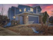 Charming two-story home featuring a two-car garage with stone accents, set against a colorful sky at dusk at 4666 Cornish Way, Denver, CO 80239