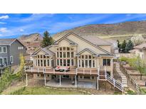 Expansive home featuring a large deck with ample seating, offering stunning views and outdoor living at 11065 W Rockland Dr, Littleton, CO 80127