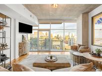 Modern living room with a large window offering city views and a balcony space at 1700 Bassett St # 2216, Denver, CO 80202