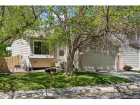 Charming home featuring a two-car garage, quaint front yard, and mature trees providing ample shade at 17611 Hoyt Pl, Parker, CO 80134