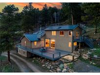 Inviting home with a metal roof, a spacious deck for entertaining, and a rustic setting, blending comfort and natural beauty at 20951 Pleasant Park Rd, Conifer, CO 80433