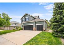 Charming two-story home featuring a three-car garage, green lawn, and lush landscaping at 10802 W Indore Dr, Littleton, CO 80127