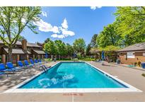 Community pool with lounge chairs and lush landscaping and blue skies with some cloud coverage at 9400 E Iliff Ave # 88, Denver, CO 80231