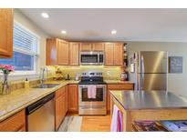 A modern kitchen with stainless steel appliances, light wood cabinets, and granite countertops at 5809 S Pearl St, Centennial, CO 80121