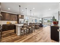 Open-concept kitchen features wood floors, stainless appliances, large island with bar seating, and easy access to a living area at 5670 Pinto Valley St, Parker, CO 80134