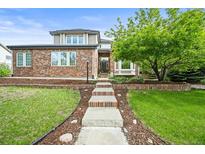Charming brick home with a well-manicured front yard, garden beds, and steps to the front door at 15756 E Aberdeen Ave, Centennial, CO 80016