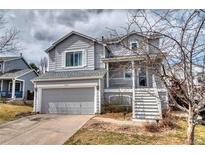 Charming gray two-story home featuring a front porch, attached garage and beautiful landscaping at 8459 Sweet Clover Way, Parker, CO 80134